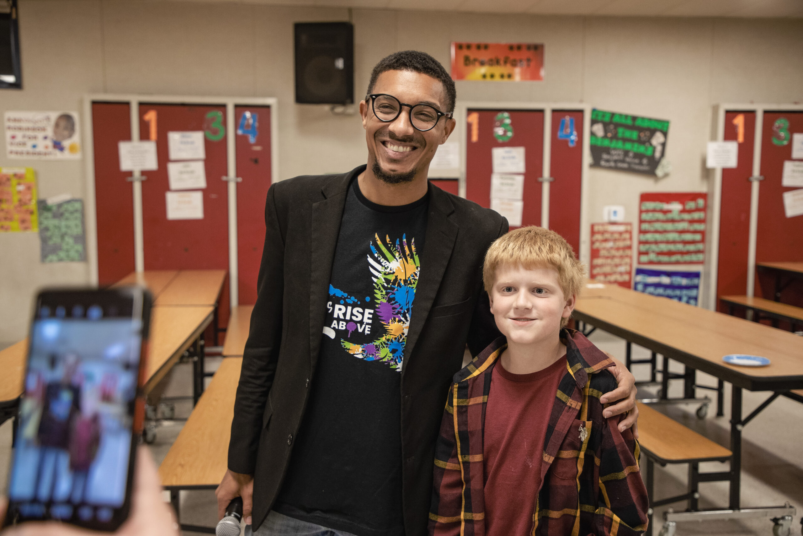 A Let’s Rise Above mentor and a student smiling together at school